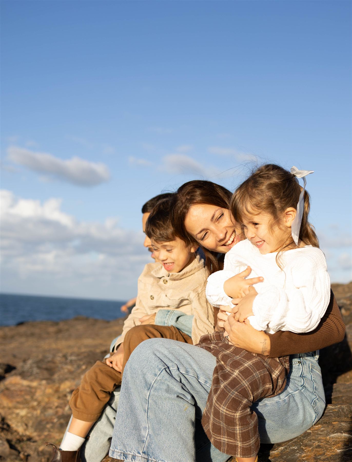 Mother laughing with her two children on seaside rocks