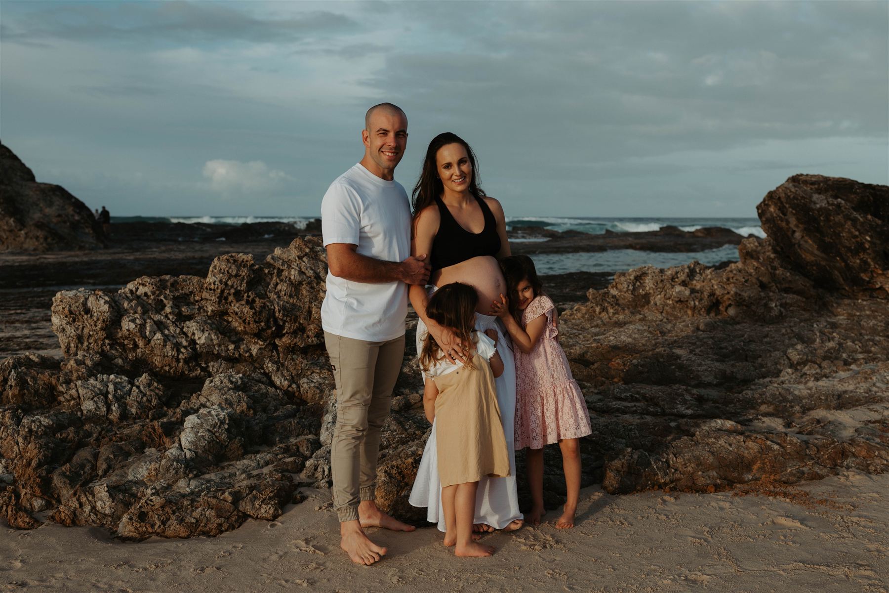 Family standing together on the beach at dusk