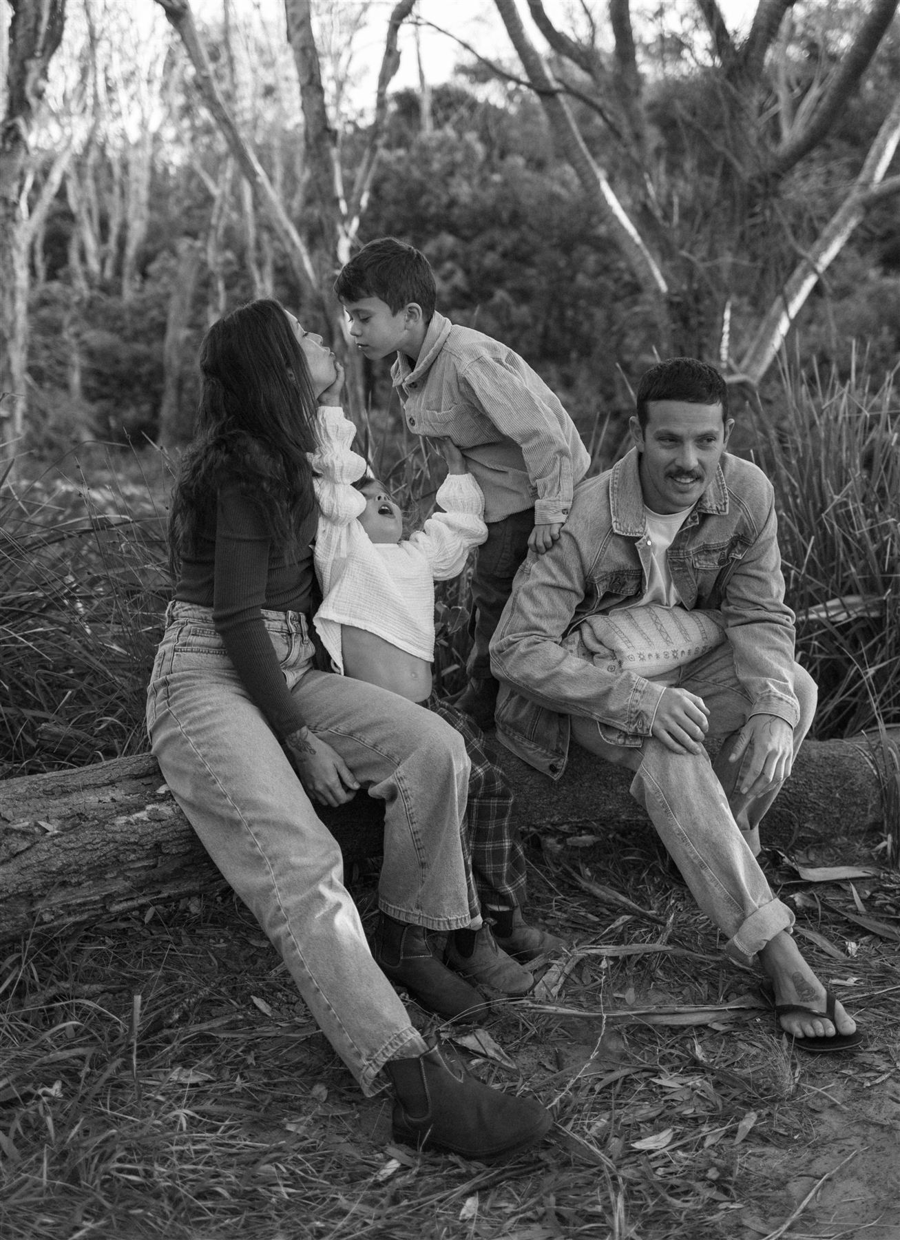 Black and white photograph of a boy kissing his mother in the bush at dusk